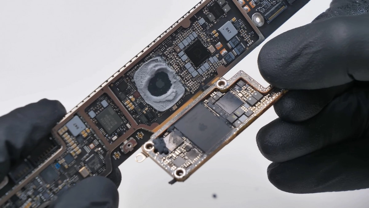 Technician holding modular MacBook Neo logic board components.