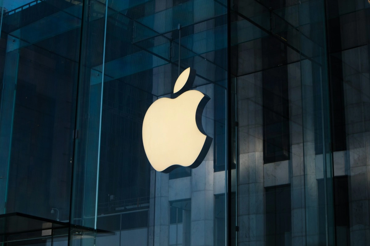 Illuminated Apple logo on glass building exterior.
