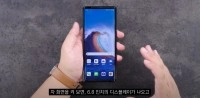 Hands holding an LG smartphone with wallpaper displayed.
