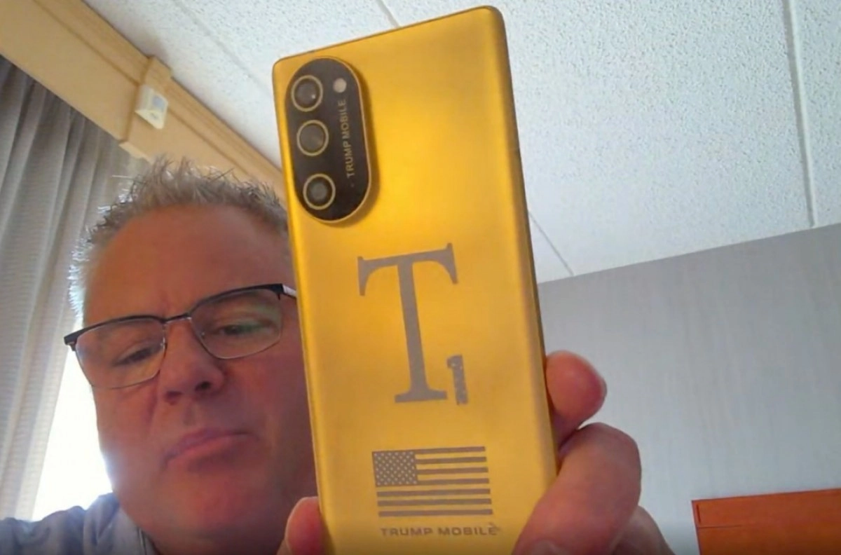 Man holding golden Trump Mobile T1 phone.