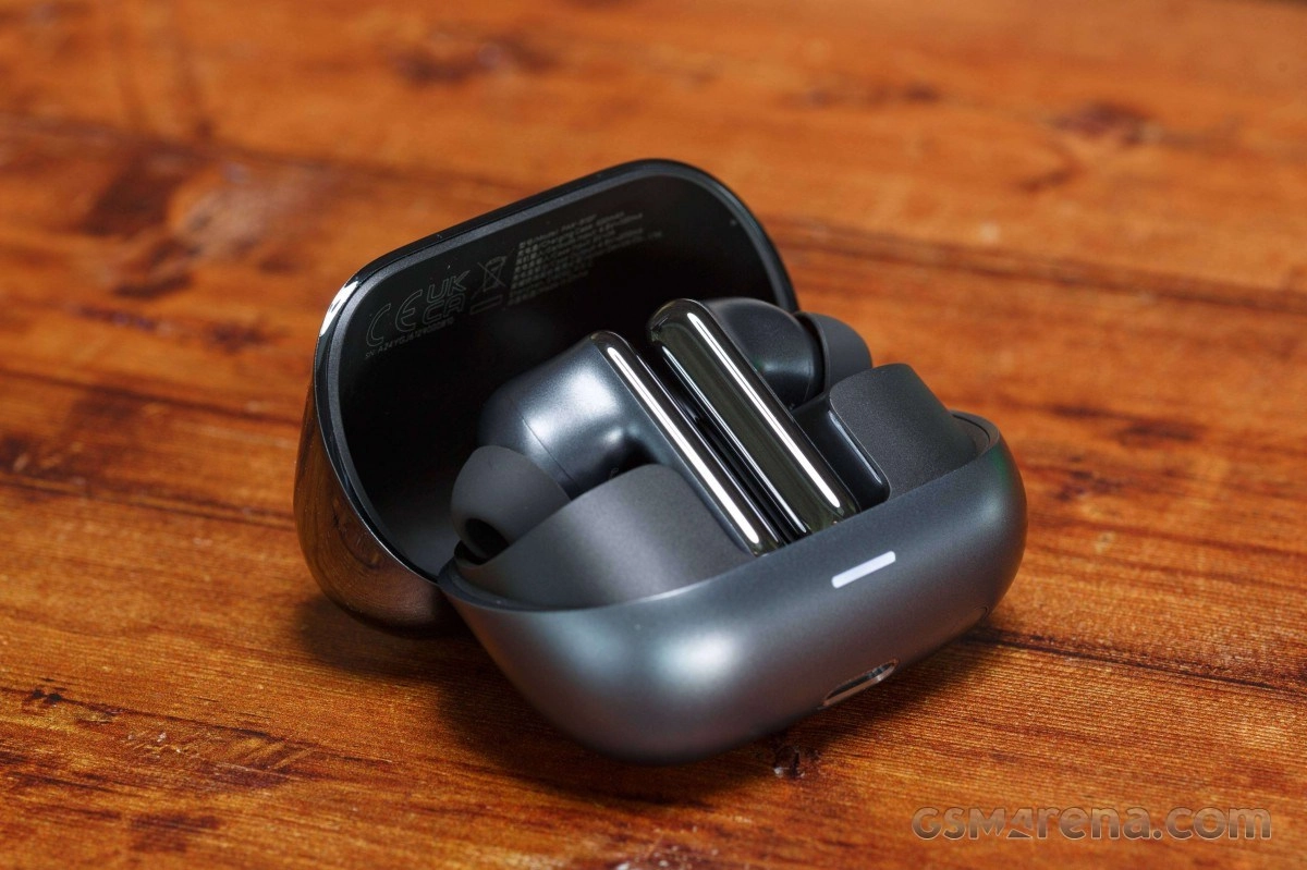 Honor earbuds with charging case on wooden surface.