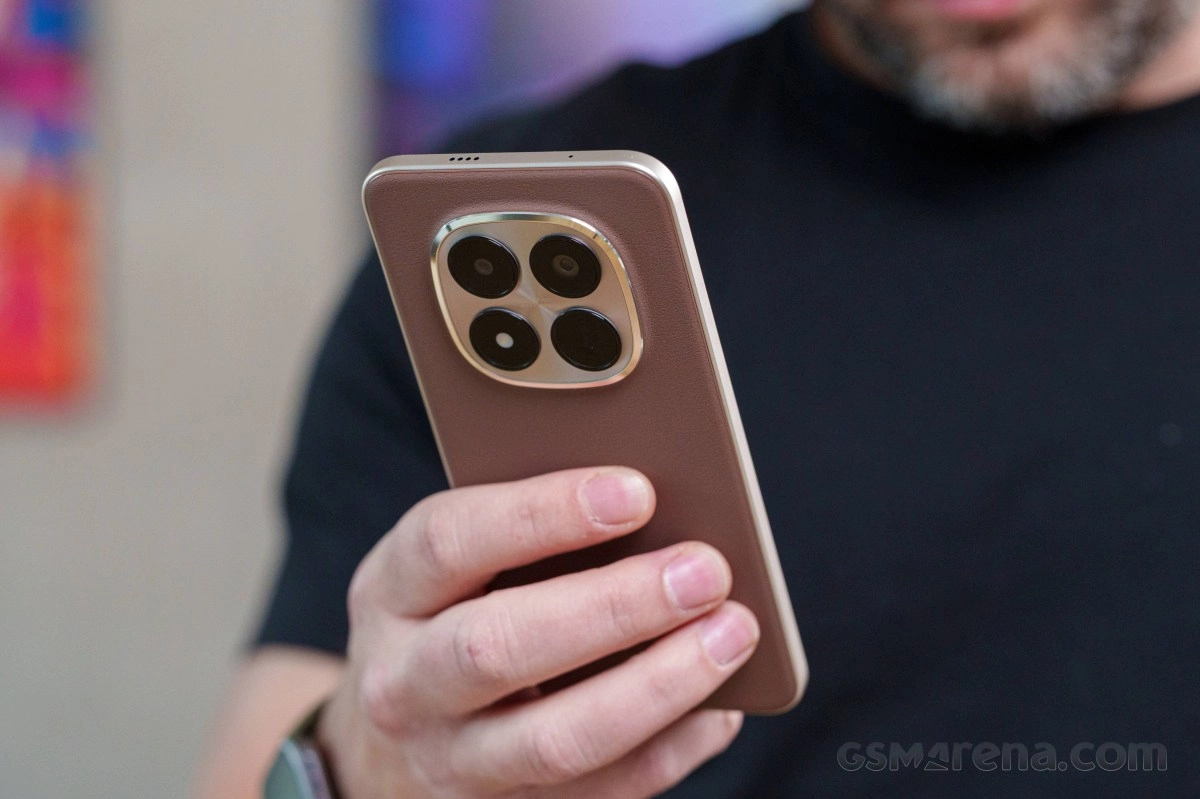 Person holding brown smartphone with prominent quad camera.
