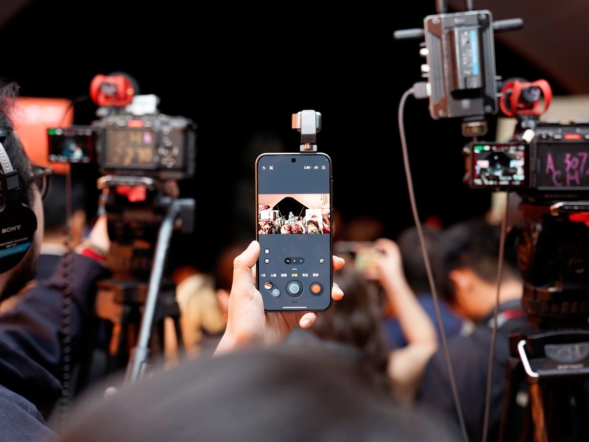 Phone records event with cameras in background.