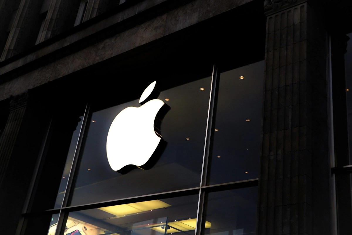 Glowing Apple logo on dark store facade.