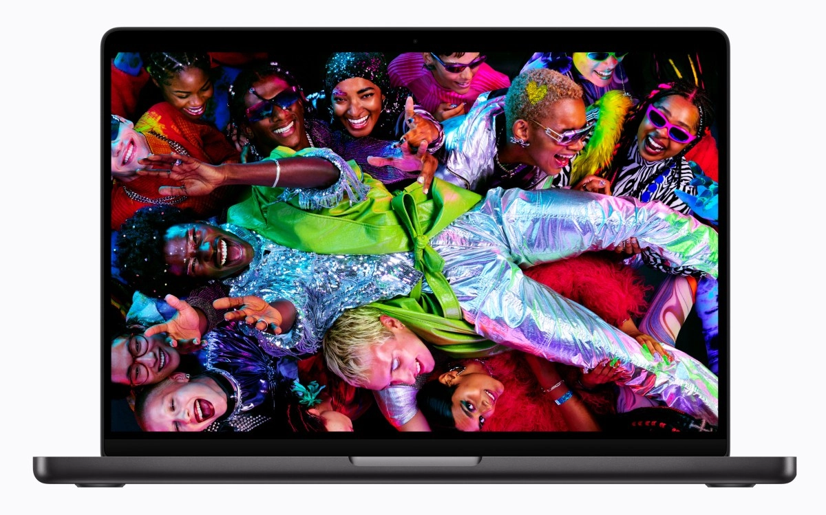 MacBook Pro OLED screen shows vibrant group portrait.