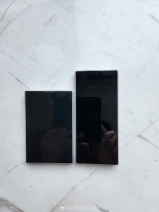 Two black smartphones on marble surface.