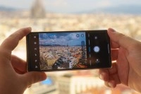 Hands holding Motorola Razr Fold taking city photo.