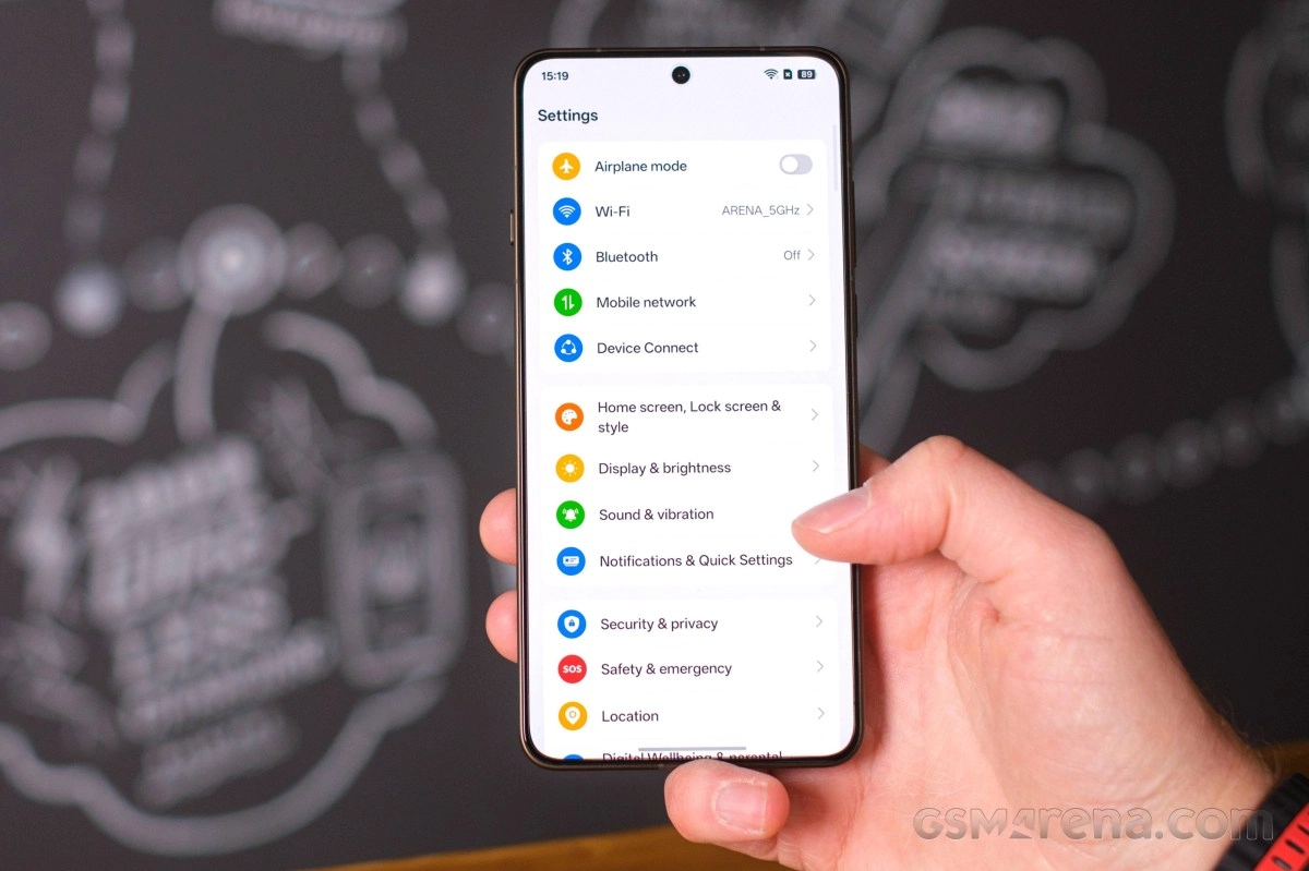 Hand holding smartphone with ColorOS settings interface.