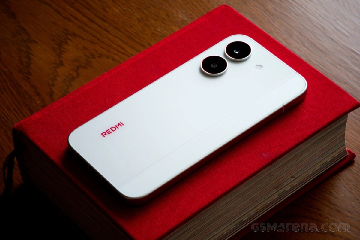 White Redmi Turbo 5 phone on red book.