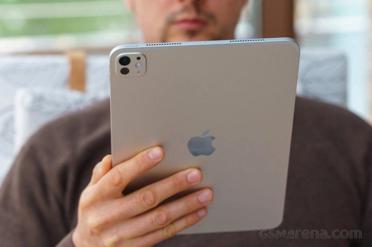 Person holding silver iPad with dual rear cameras.