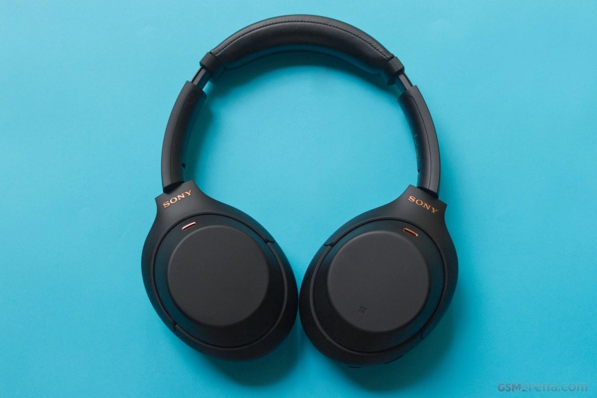 Black Sony WH-1000XM5 headphones on blue background.