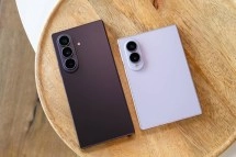 Two Samsung foldable phones on a wooden surface.