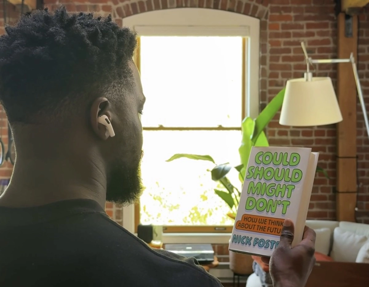 Man wearing AirPods, holding book "Could Should Might Don't".