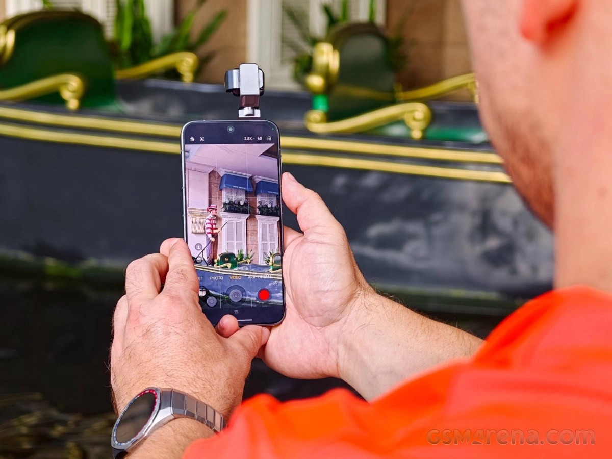 Hands holding Honor phone with gimbal stabilizer.