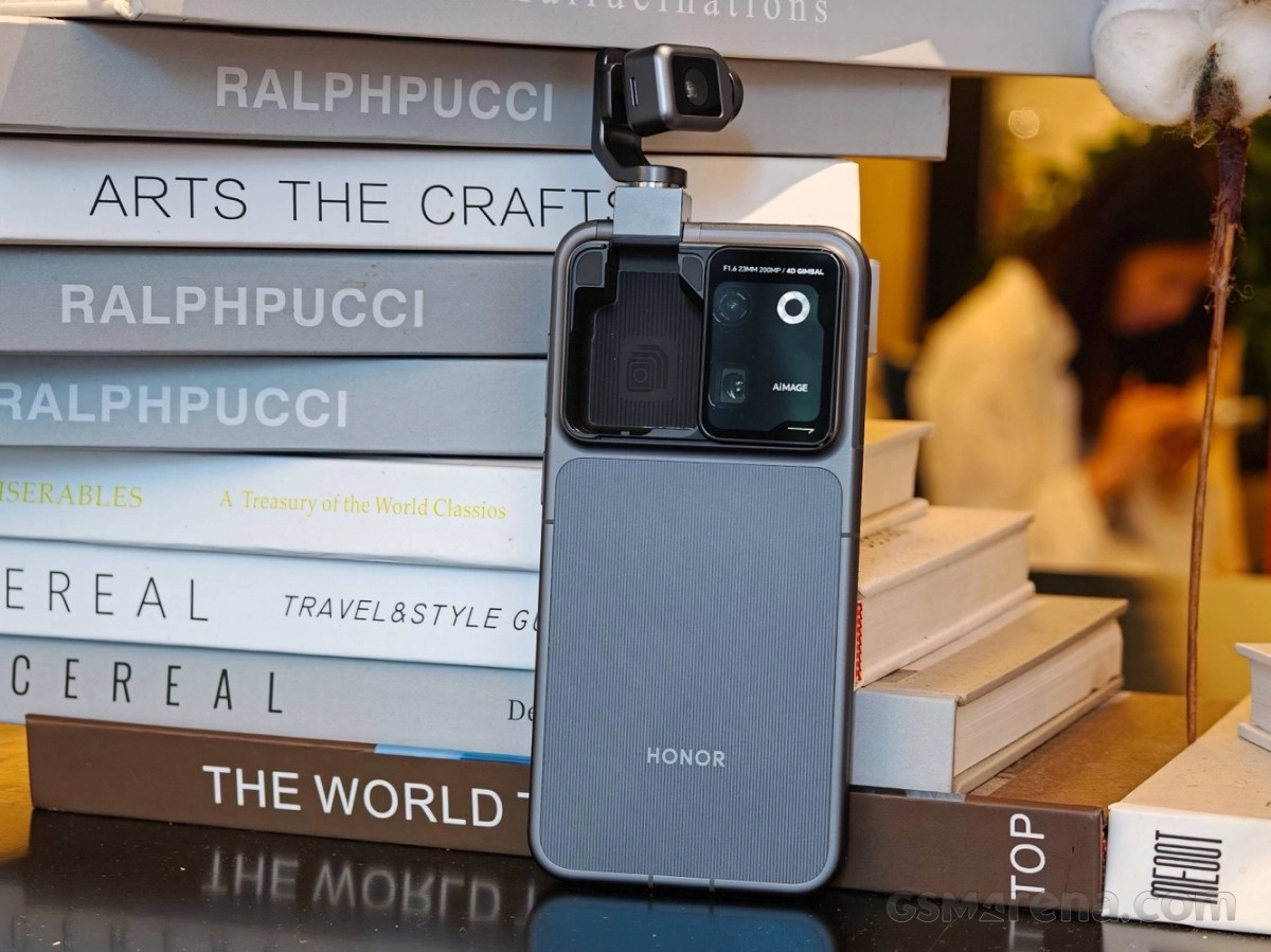 Honor phone with gimbal camera, stacked on books.