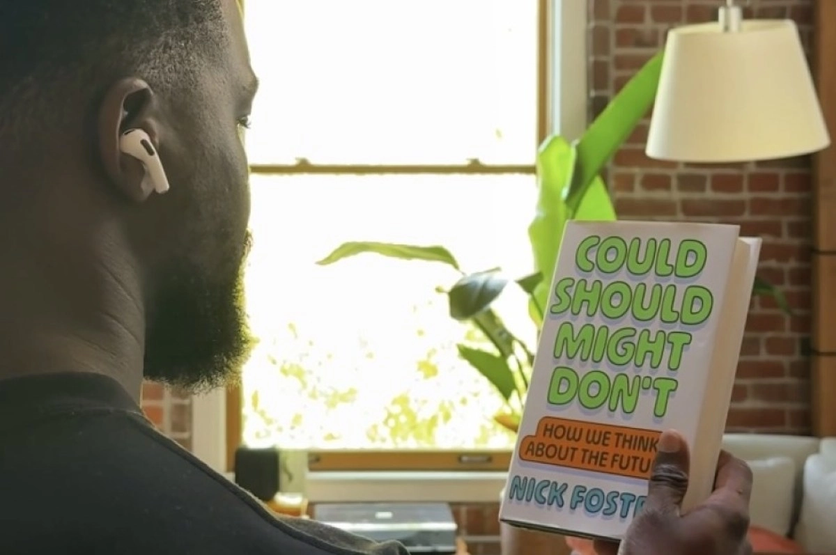 Man wearing AirPods, holding "Could Should Might Don't" book.