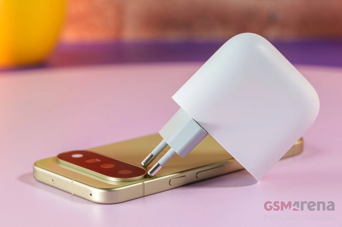 Pixel phone charging with white adapter on pink surface.