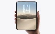 Foldable phone held in hand with desert landscape.