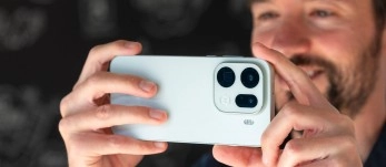 Smartphone with triple-lens camera held by hands.