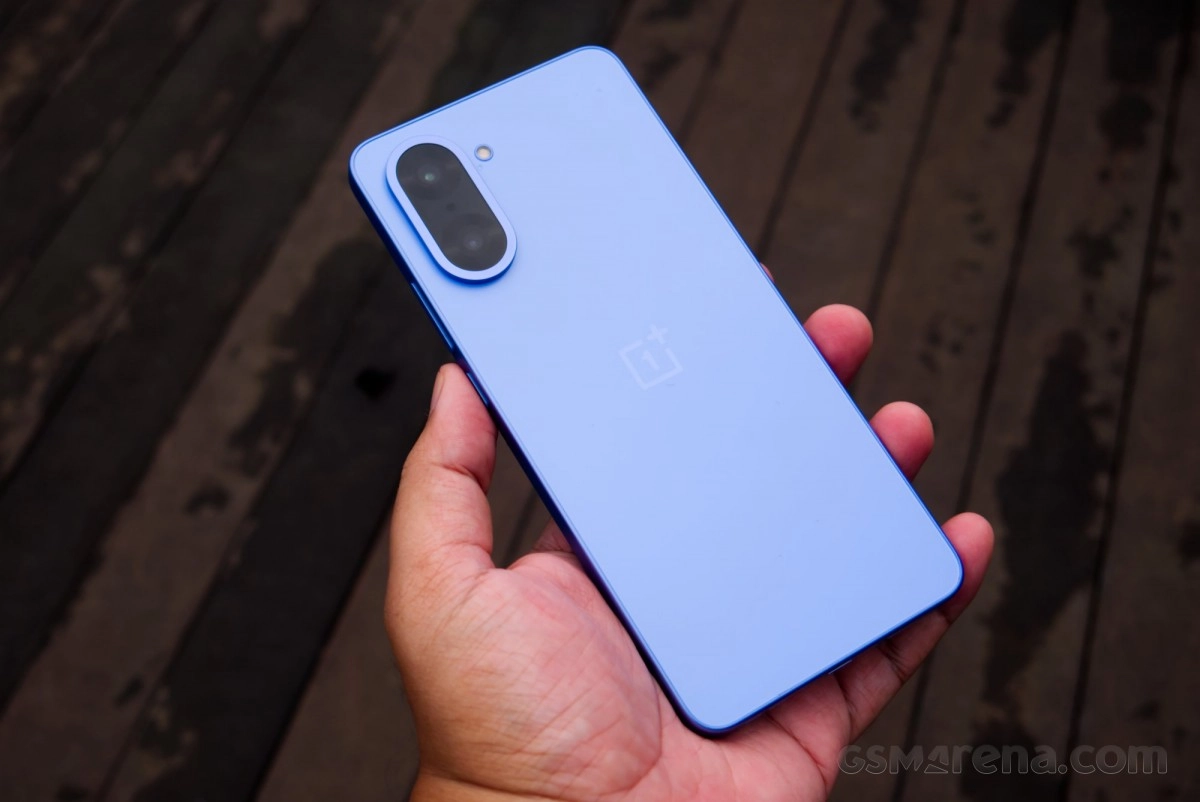 Light blue OnePlus smartphone back held in hand.