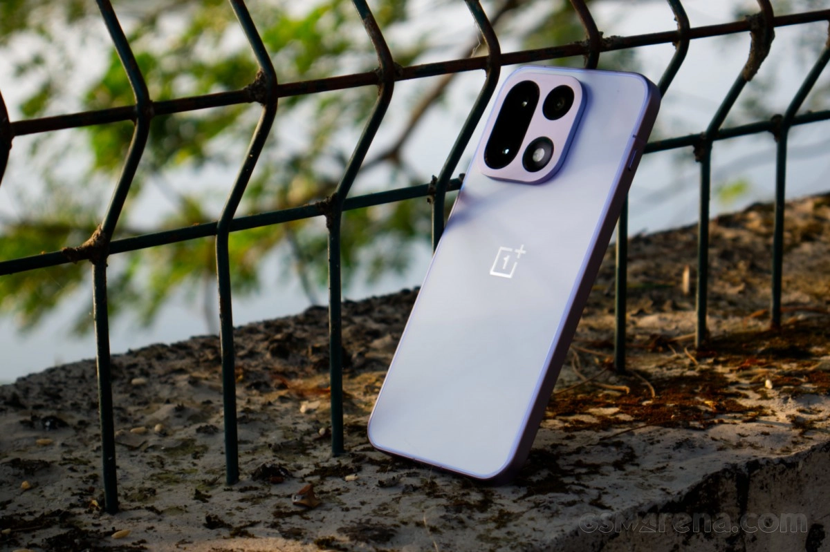 Purple OnePlus phone resting against metal fence.