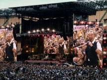 Singer performing at large outdoor music concert.