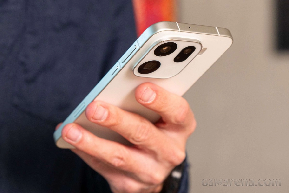 Hand holding white smartphone with triple cameras