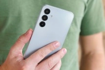 Gray smartphone with triple camera, held.