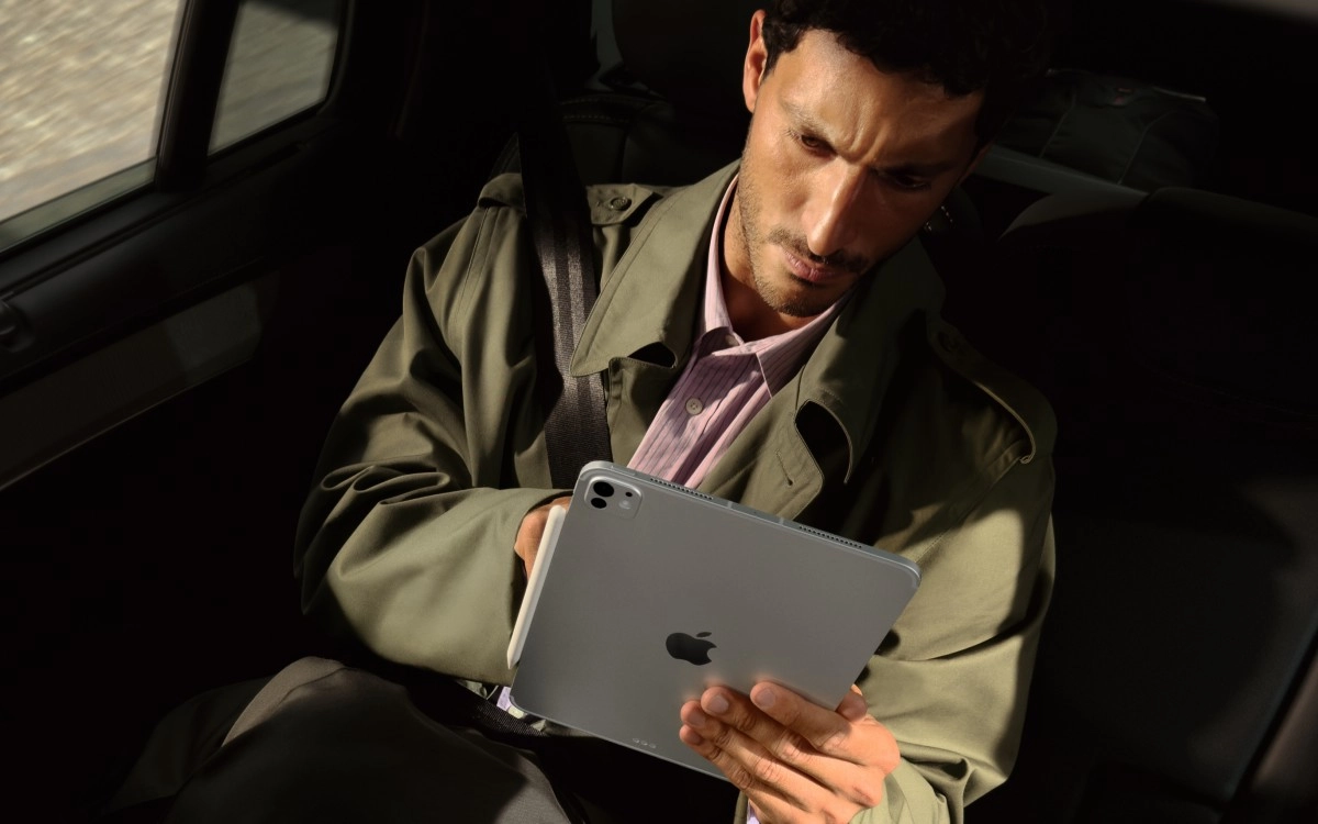 Man holding silver iPad Pro in car.